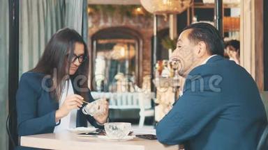 两个商务人士握手，他们吃商务午餐。 在餐馆或咖啡店里的女人和男人