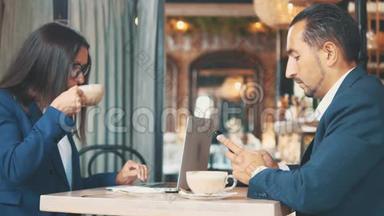 两个商人吃商务午餐。 在一家餐馆或咖啡店里，女人和男人正在搅拌和