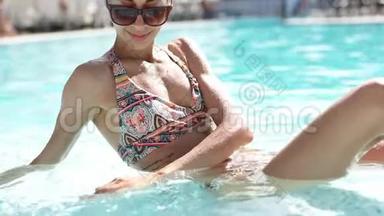 美丽的女孩戴着黑色太阳镜，拥有惊人的超级苗条身材，在<strong>游</strong>泳池放松，享受温暖的<strong>夏日</strong>