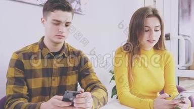 可爱的一对夫妇坐在咖啡馆的桌子旁。 他们正在手机上输入新的信息。 快关门。 复制空间
