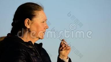 中年妇女缓慢地<strong>点燃</strong>一支香烟