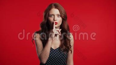 <strong>积极</strong>的女孩拿着手指在她的嘴唇上的红色背景。 什赫的<strong>姿态</strong>
