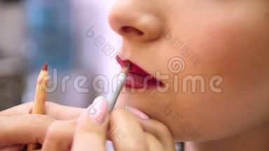 化妆师描绘了年轻<strong>女孩</strong>的嘴唇。 用刷子涂你的嘴唇。 红色。 化妆师化妆