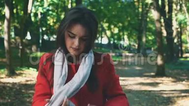 漂亮的年轻女孩穿着红色外套，轻轻地系着一条粉红色的围巾，与世隔绝，在公园模糊的背景上。 快关门。 复制空间