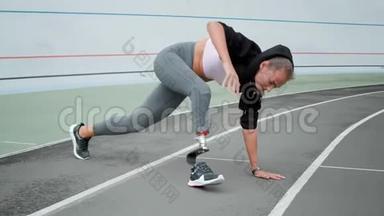 残疾妇女在体育场伸腿。 女孩在运动跑道上练习瑜伽