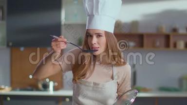 厨师在厨房品尝汤。 穿制服的女人在炉子上煮汤