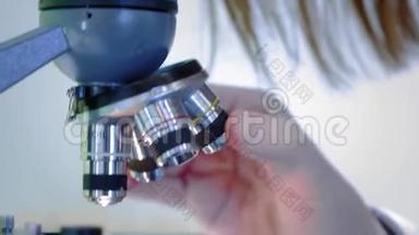 年轻的女科学家透过显微镜看。 她研究样本。 一位年轻的科学家进行科学研究