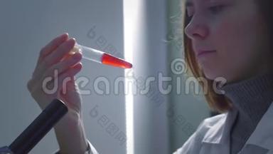 年轻的女科学家用血液检查试管。 她研究样本。 一位年轻的科学家进行科学研究