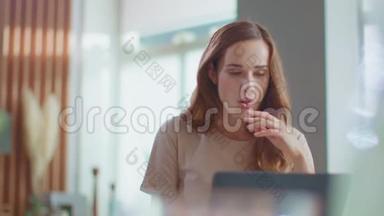 微笑的女商人在家里办公室用笔记本电脑打字。 女孩在笔记本电脑上聊天