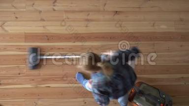 打扫房子。 一个女人在公寓里吸木地板，俯视