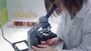 年轻的女科学家透过显微镜看。 她研究样本。 一位年轻的科学家进行科学研究