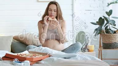 快乐的怀孕妈妈在床上吃披萨。 贝莉妈妈吃意大利菜