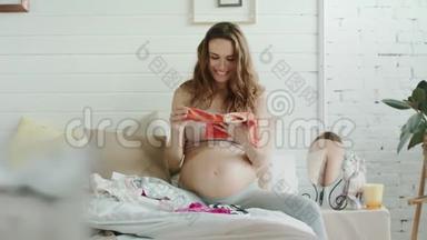 快乐的孕妇，在卧室里考虑婴儿用品。