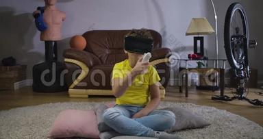 白人男孩在虚拟现实谷歌持有遥控器和弯曲。 穿黄色T恤和蓝色牛仔裤的男生