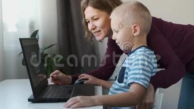 在家里和妈妈一起在电脑上工作的男孩。 电子课程，儿童教育。