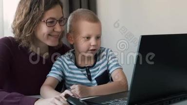 在家里和妈妈一起在电脑上工作的男孩。 电子课程，儿童教育。