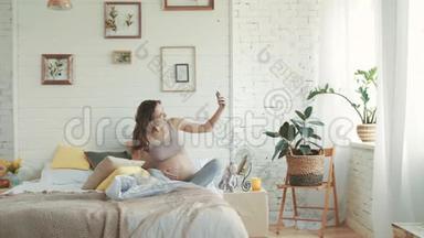 开朗的准妈妈拍自拍<strong>照片</strong>.. 坐在床上的<strong>孕妇</strong>。