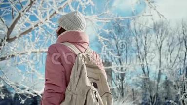 在温暖的粉红色公园里慢动作的年轻女子，在白雪皑皑的冬日公园里散步
