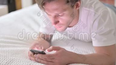 野心勃勃的年轻人在床上玩智能手机