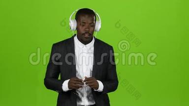 黑人<strong>非洲</strong>男子通过耳机听<strong>音乐</strong>，并一起唱歌。 绿色屏幕