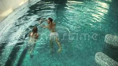 上图为幸福夫妇在游泳池游泳。 一对漂亮的情侣在游泳池里放松
