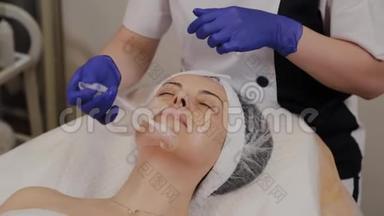 专业美容师从女人的脸上取出透明`织物抗衰老面膜。