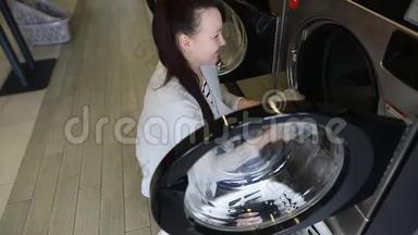 漂亮的年轻女人把脏衣服放进洗衣机洗衣服，洗衣服