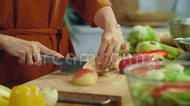 女人的手在厨房桌子上切红苹果。 女孩在家品尝切片苹果