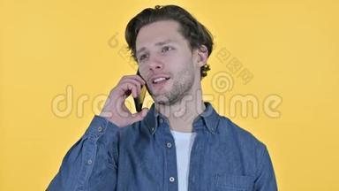 黄色背景下的年轻人在智能手机上讲话的肖像