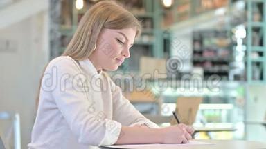 一个认真的年轻女人在咖啡馆做文书工作