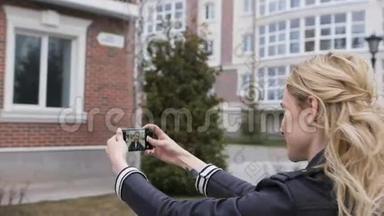 一个美丽的金发女孩的侧面肖像，她用智能手机上网，在一个郊区的家中拍摄自拍照片