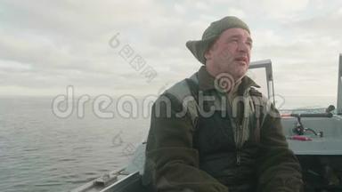 船上的白人渔夫。 他<strong>很累</strong>，但<strong>很</strong>满意。 美丽的水面和天空是背景。
