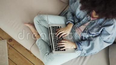 女人正在写打字，坐在沙发上的笔记本电脑，俯视。