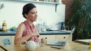 女人在视频通话中把茶倒进杯子里。 女孩用笔记本电脑进行视频聊天。