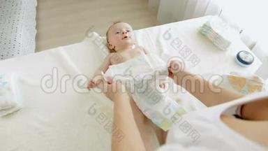 年轻的母亲给3个月大的婴儿换<strong>尿布</strong>，躺在换<strong>尿布</strong>的桌子上