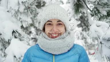 可爱的微笑的年轻女子，戴着温暖的羊毛帽和长长的围巾，在白雪皑皑的冬季<strong>公园里散步</strong>。