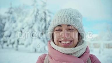 慢镜头特写照片：穿着<strong>粉色</strong>大衣的开朗<strong>微</strong>笑的女人在阳光下的雪地公园里堆雪