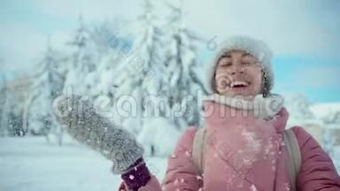 慢镜头特写照片：穿着粉色大衣的开朗微笑的女人在阳光下的雪地公园里堆雪