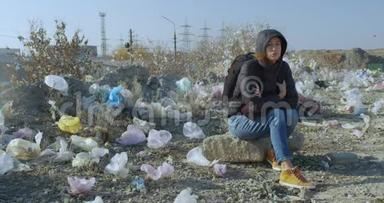 一个女孩坐在一个被塑料袋污染的地方。 地球污染的规模令人印象深刻。