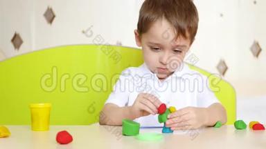 一个小男孩坐在桌子旁，花时间雕刻粘土。 游戏，幼儿`发展，幼儿`时间..