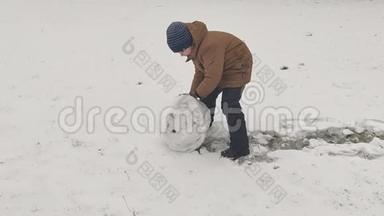 男孩为雪人滚一个大雪球