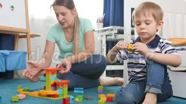 4k视频：小男孩和妈妈一起在卧室的地板上搭建一座五颜六色的砖块和积木塔
