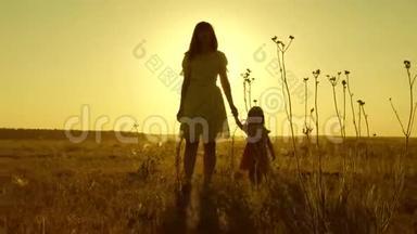 幸福童年的概念.. 小女儿和妈妈牵着手在田里走来走去。 宝贝牵着妈妈`手。 快乐