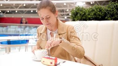 4K画面显示，一位年轻的微笑女子坐在咖啡馆里，打开纸袋，装满糖，倒在咖啡杯里，喝着
