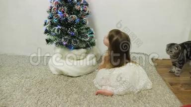 一个小<strong>女孩</strong>和一只猫在孩子们`房间里的<strong>圣诞树</strong>附近玩耍。 宝贝和<strong>圣诞树</strong>。 圣诞节假期
