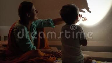 4k视频：年轻母亲在晚上睡觉前与小儿子一起在<strong>皮影</strong>戏或木偶戏中玩耍