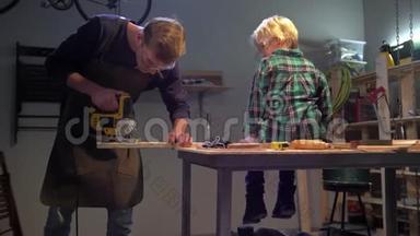 男孩坐在船上，男人把钉子钉在桌子上的木板上