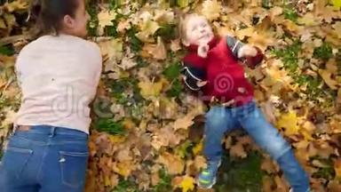 4k视频：妈妈带着小儿子在草<strong>地上滚动</strong>，上面覆盖着黄色落叶