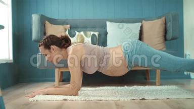 特写<strong>孕肚</strong>妈妈在轻客厅练习瑜伽木板姿势..