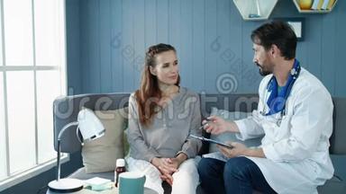 漂亮的孕妇在柜子里的沙发上和医生说话。